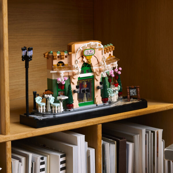 Miniature café en briques LEGO, décor détaillé avec lampadaires, tables, chaise, fleurs, et fenêtres, parfait pour la décoration ou la collection LEGO.