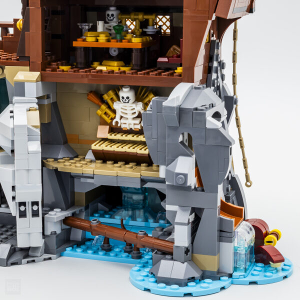 Vieux château en briques LEGO avec décorations de pirates et skeletons, éléments d’eau bleue, pont en bois et détails détaillés pour jeux créatifs et collection.